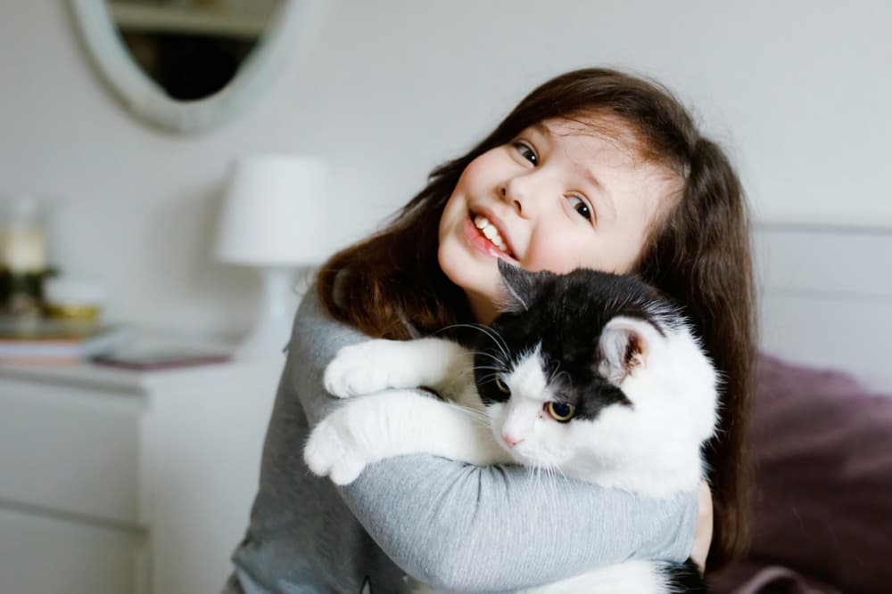 Child holding cat happily